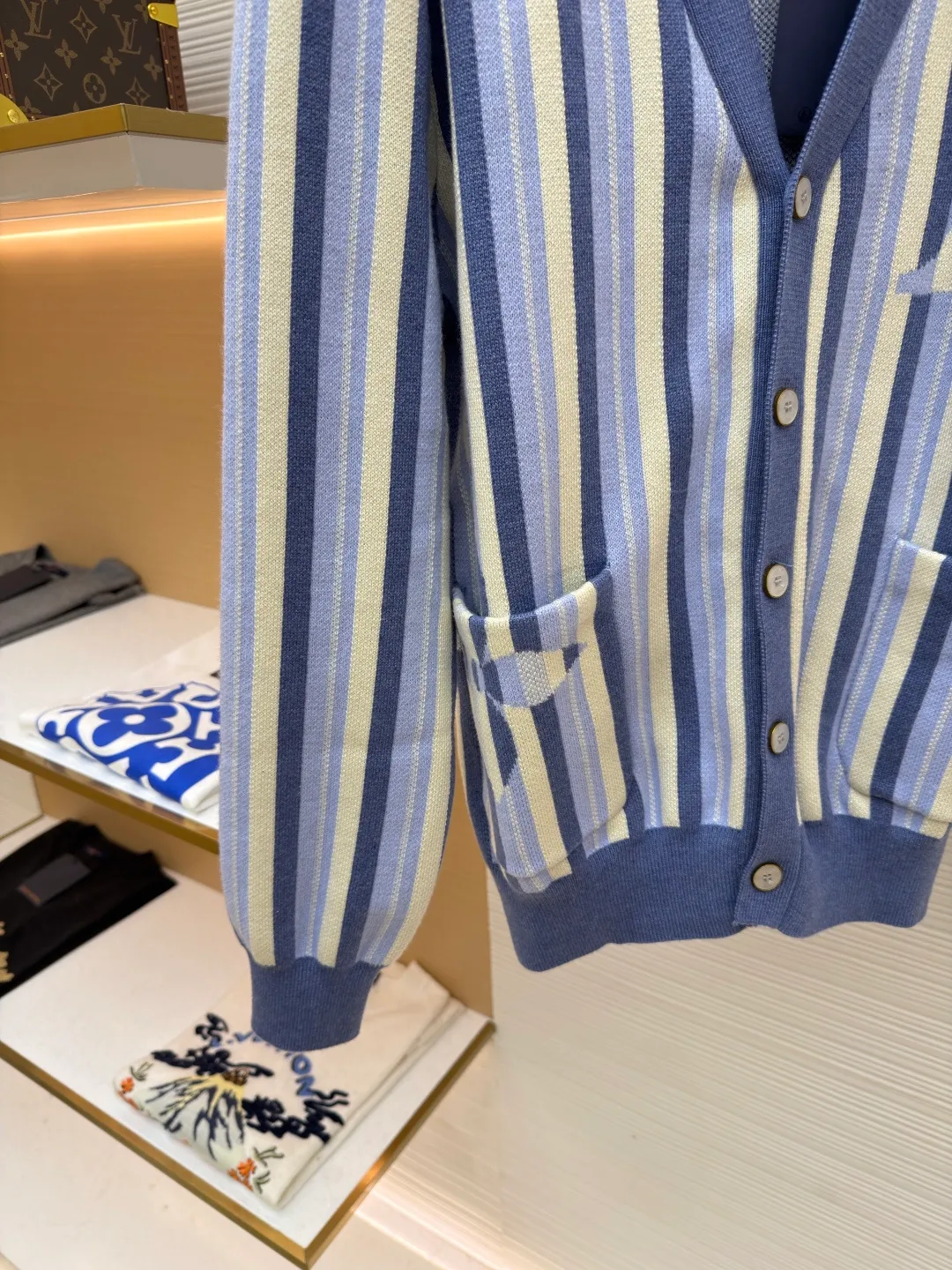 LOUIS VUITTON striped jacquard single-breasted sweater ●Original version: Purchased and developed for 15100 ●Item number: 1682314-C00 ●Fabric: wool fabric ●Technology: jacquard knitting ●Color: blue ●Version: fitted version ●Weight: about 930 grams ●Size: S-M-L-XL ●Description: This LV striped knitted cardigan is made of high-count worsted wool blended yarn. The double-ply threading process enhances the yarn's toughness. It is not easy to pill and has an outstanding drape feeling. The body of the garment adopts vertical jacquard weaving technology, with navy blue, light blue and off-white yarns interlaced with each other. The stripe width and spacing are precisely controlled by a computerized flat knitting machine, so that the color transition is natural and even. The LV letter jacquard on the left body has been debugged several times through plate making to ensure that the pattern is three-dimensional and clear. The V-neck, cuffs, and hem all use ribbing technology and are pre-shrunk to shape, making them less likely to loosen and deform after long-term wear. The buttons are made of custom-made metal, with matte sandblasting on the surface, and are hand-stitched with the seams of the body. The pockets use welting technology, and the edges are flat without jumpers. Every detail reflects the exquisite clothing craftsmanship and brand ingenuity. The overall wiring is straight and delicate, the fabric is comfortable and soft, and the color is consistent without color difference. It can be matched with the same style to create a fashionable look and control various occasions. Customized accessories, complete with three standards, same style for men and women!